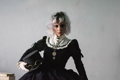 Woman wearing costume while sitting against wall at home