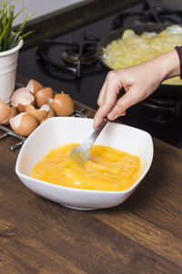 Cropped hands of woman mixing eggs in bowl on table