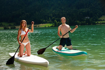 Couple paddleboarding on lake