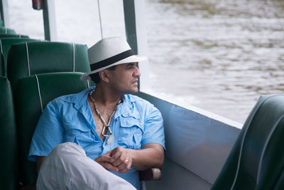Young man looking at camera while sitting on boat