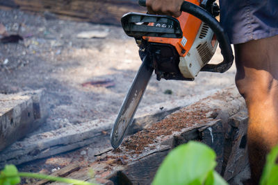 Midsection of man with chainsaw standing on land