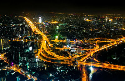 High angle view of illuminated city by buildings at night