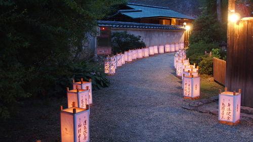 Illuminated lantern by road against sky at night