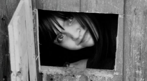 Portrait of confident peeking through window