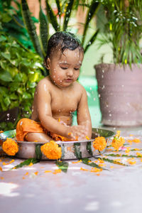 Cute toddler baby boy bathing in decorated bathtub at outdoor from unique perspective