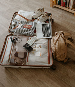 Open baggage with snickers, sweater, laptop, headphones and passport, vintage camera and backpack.