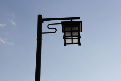 Low angle view of silhouette street light against blue sky
