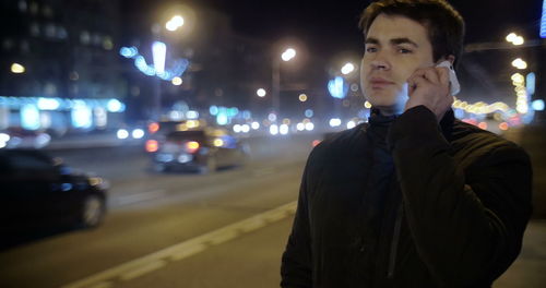 Young man standing on road at night