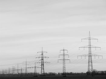 Low angle view of electricity pylon on field against sky