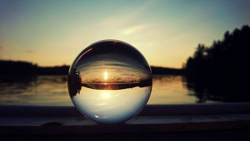 Close-up of crystal ball against sky during sunset