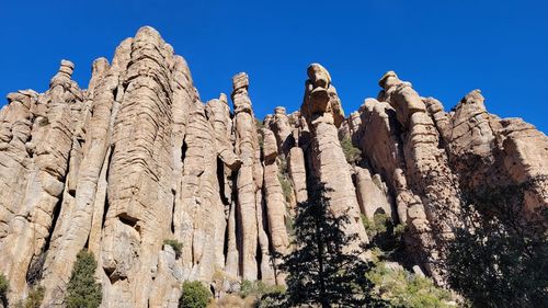 Low angle view of rocks against clear blue sky