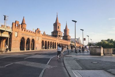 People on street amidst buildings in city against sky