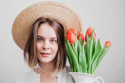 Portrait of smiling woman with flower against white background