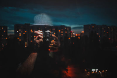 Woman photographing illuminated cityscape at night
