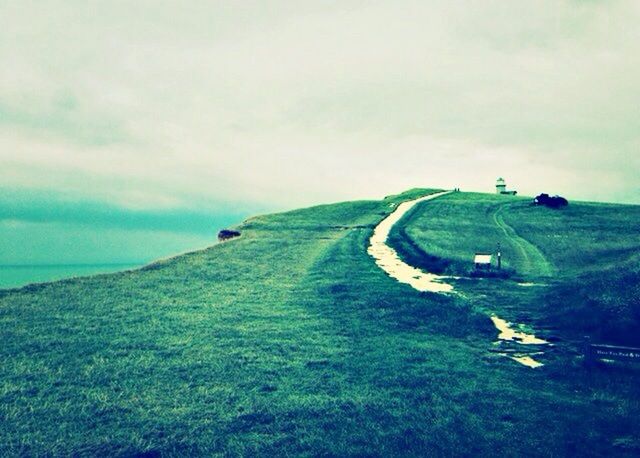 grass, sky, landscape, field, cloud - sky, green color, tranquility, tranquil scene, grassy, cloudy, nature, scenics, beauty in nature, cloud, horizon over water, non-urban scene, day, outdoors, remote, transportation