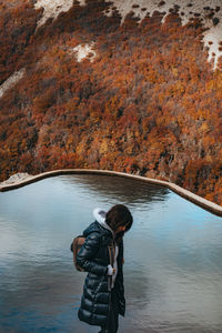 Rear view of woman standing in lake during autumn