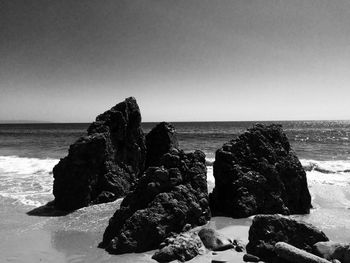 Rock formation on beach against clear sky