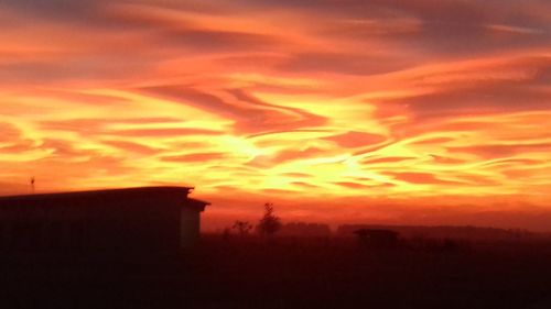 Silhouette cityscape against orange sky