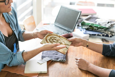 Businesswoman discussing painting with female colleague at table in home office