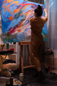 Rear view of woman painting at home