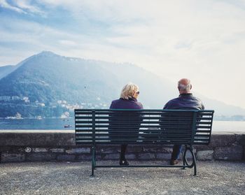 Empty bench on mountain against cloudy sky