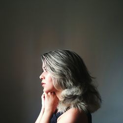 Profile view of young woman with short hair against gray background