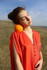 Midsection of woman with orange on field against sky