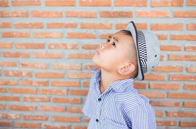 Portrait of boy standing against brick wall