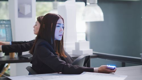 Side view of young woman using mobile phone in office