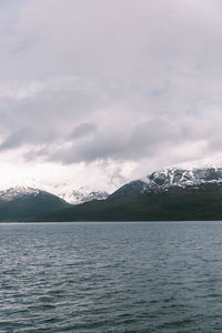 Scenic view of lake by snowcapped mountains against sky