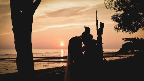 Silhouette man at beach against sky during sunset