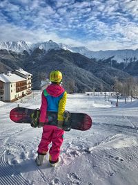 Full length rear view of woman walking on snowcapped mountain