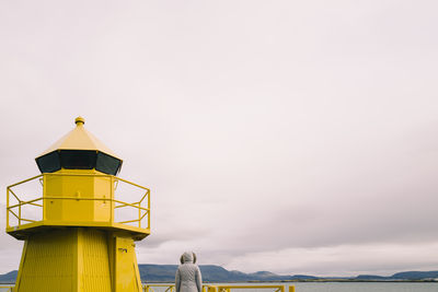 Lighthouse by sea against clear sky