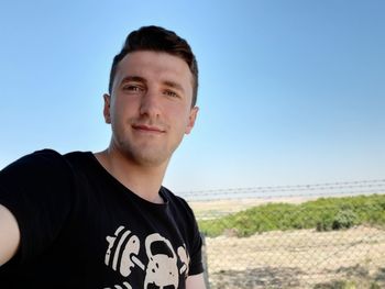 Portrait of young man standing against clear blue sky