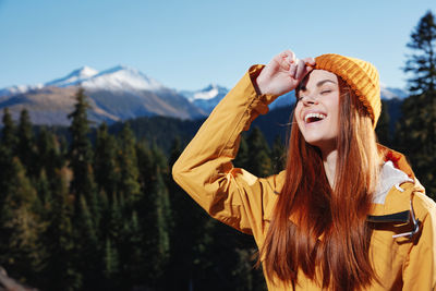 Portrait of young woman standing against mountain