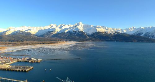 Scenic view of sea and snowcapped mountains against blue sky