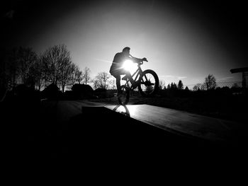 Silhouette man with bicycle against clear sky