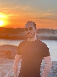 Portrait of young man standing against sea during sunset 3