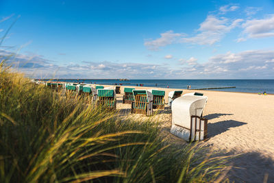 Hooded chairs on beach against sky