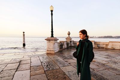 Woman standing by sea against sky