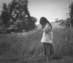 Woman standing on field against trees