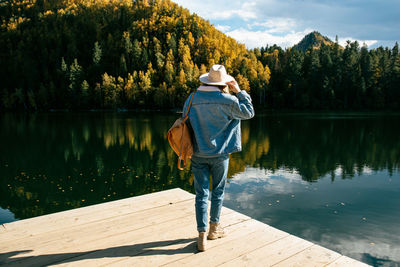 Rear view of man standing on pier over lake