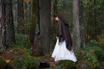 Woman standing by trees in forest