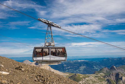 Overhead cable car over mountains against sky