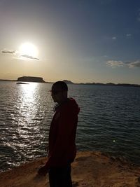 Man looking at sea against sky during sunset