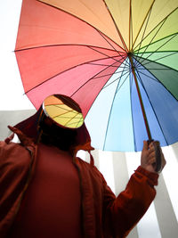 A faceless man holding multi colored umbrella