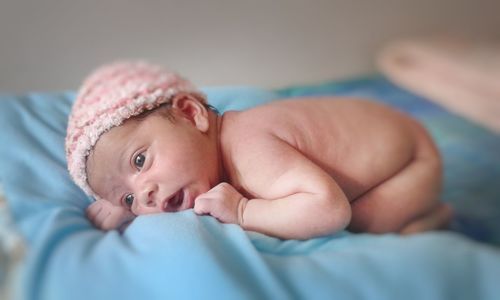 Close-up of newborn baby girl lying on bed