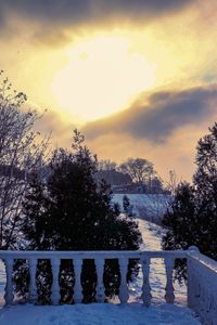 Snow covered field against sky during sunset