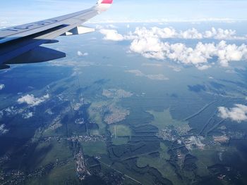 Aerial view of aircraft wing over landscape against sky