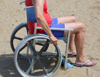 Low section of man sitting on swing at beach